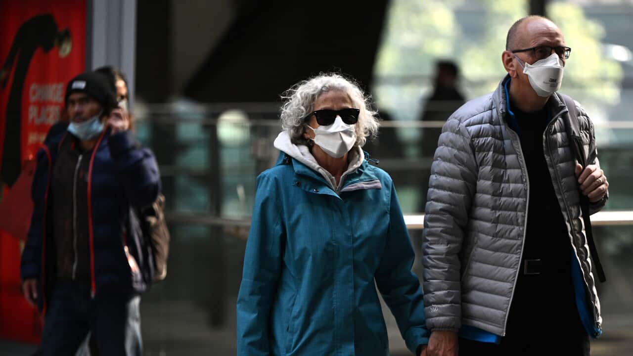 Older couple holding hands outside wearing face masks 