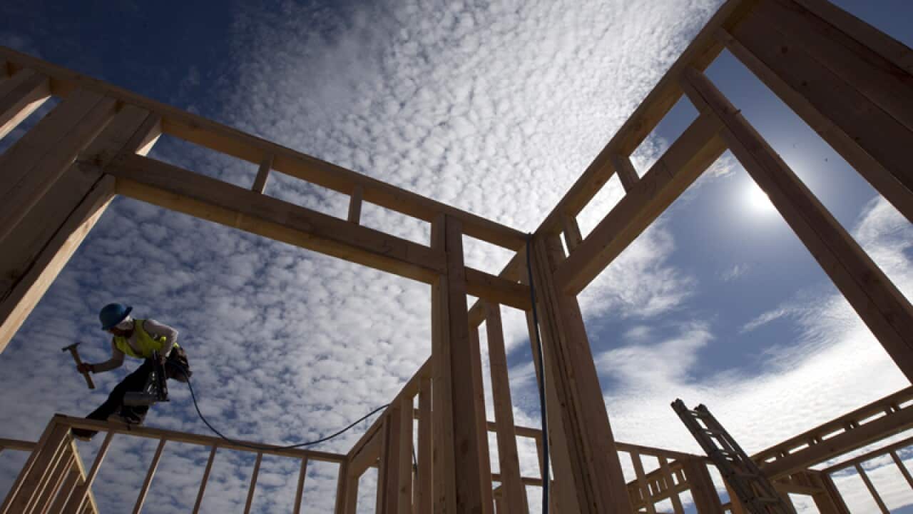 A construction worker works on a house frame in California