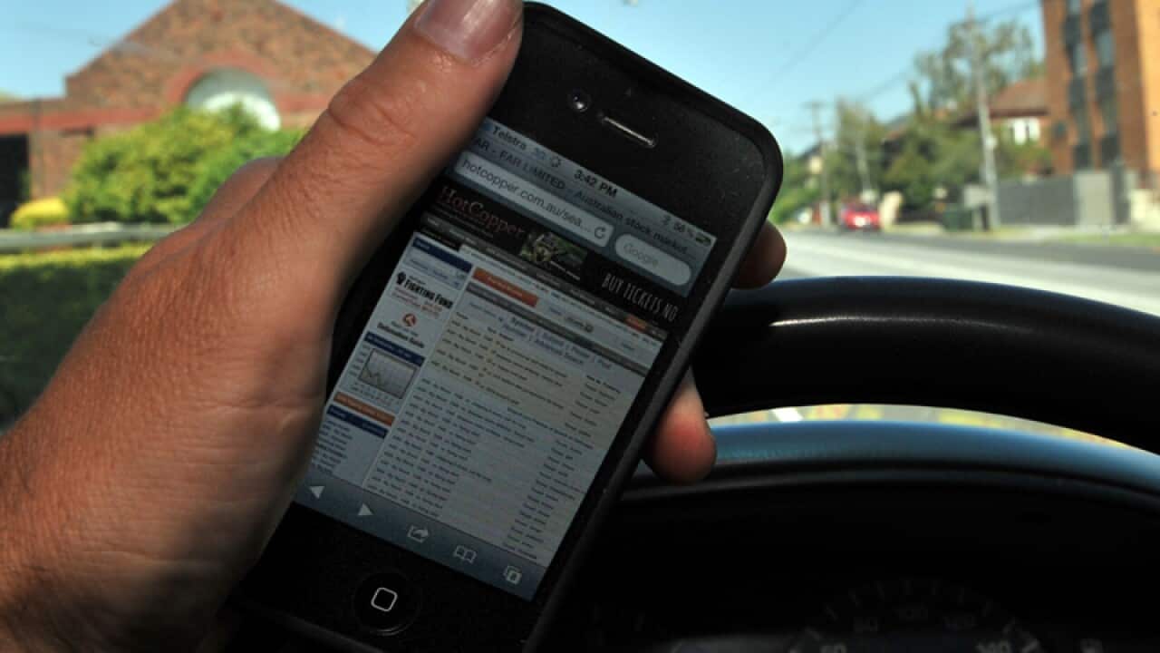 A driver holds a mobile phone whilst driving