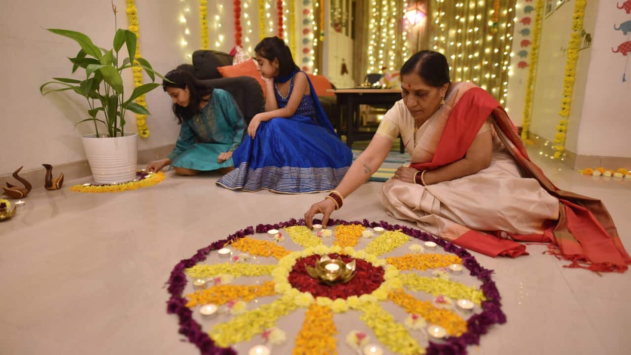 Multi-generation Indian family making floral rangoli for Diwali celebration