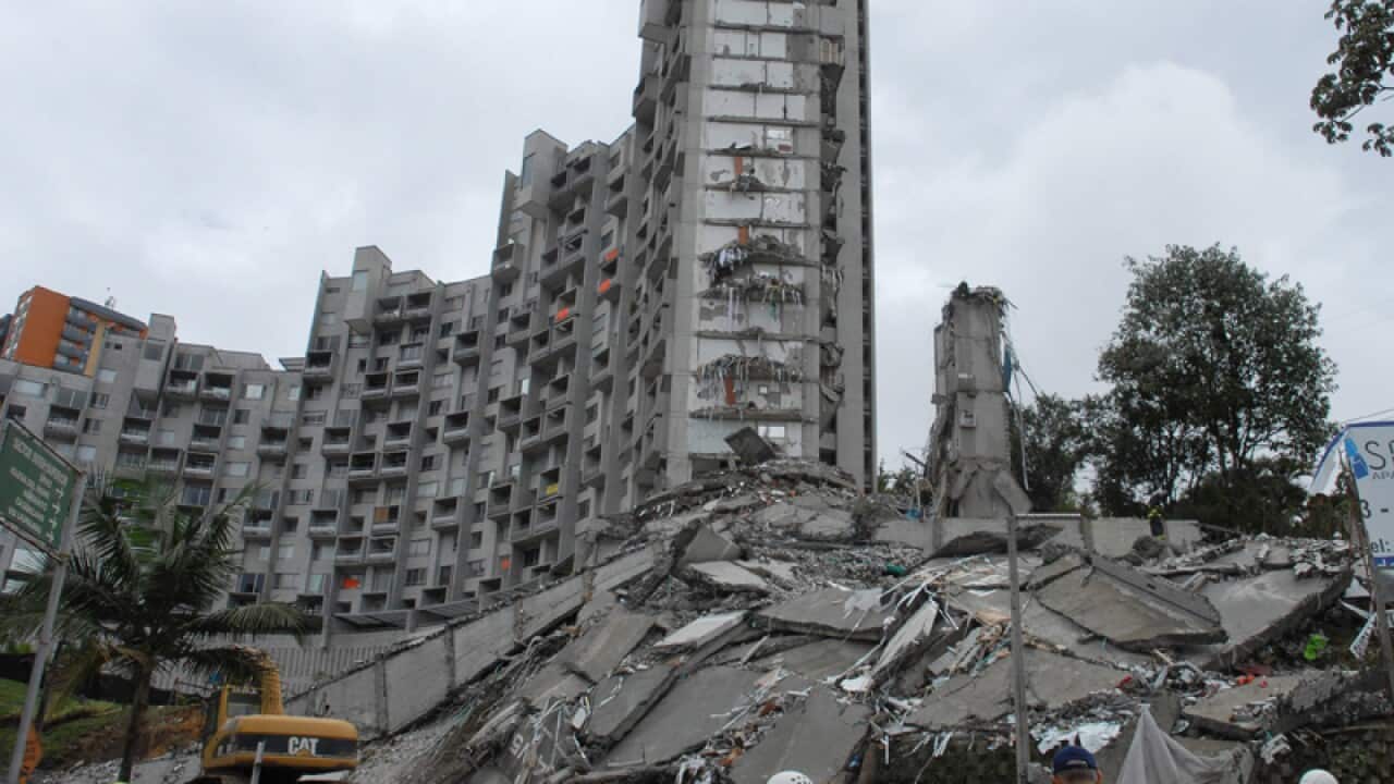Rescue workers look at the remains of a building that collapsed