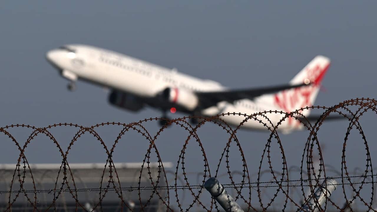 Barbed wire security fencing is seen as an aircraft takes off