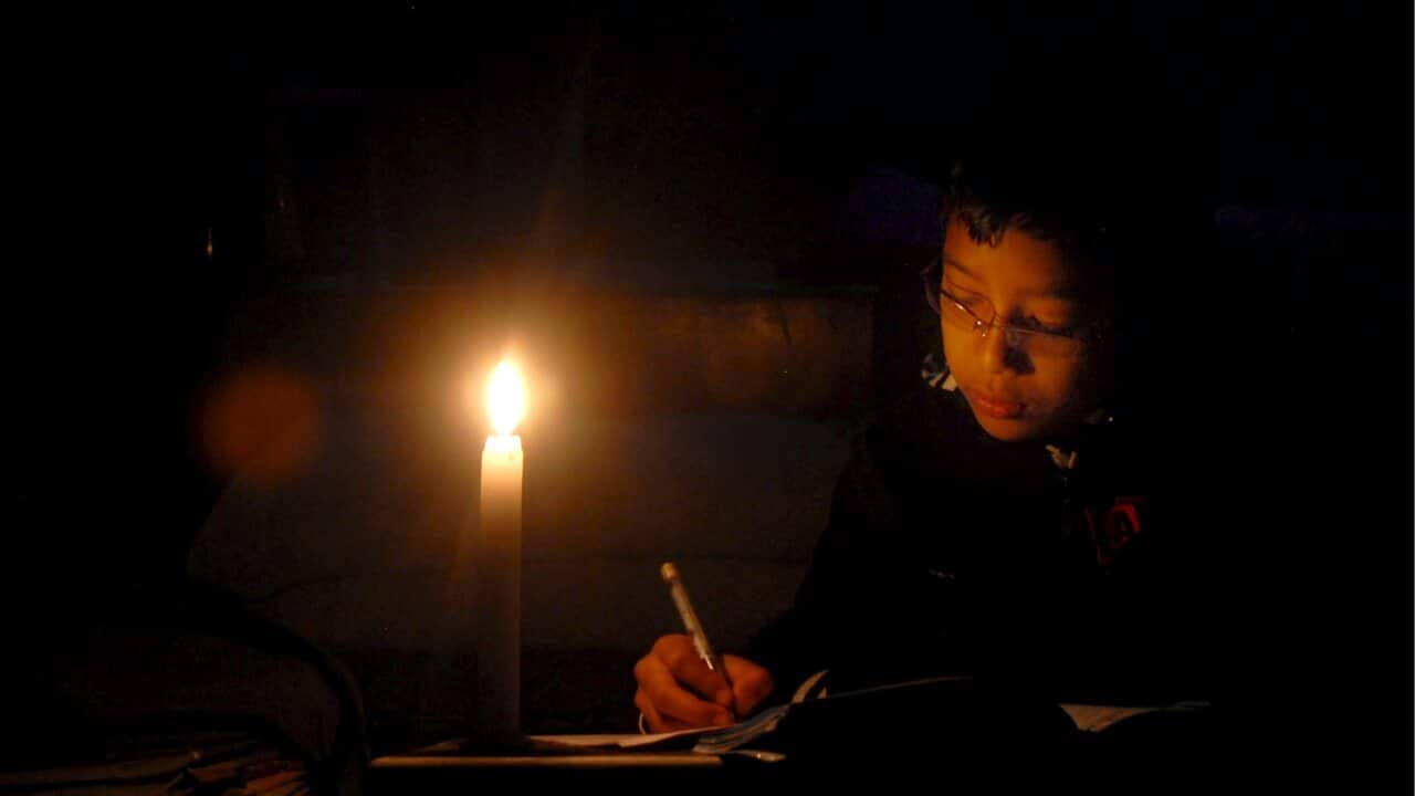 A young boy completes his homework using a candlelight during a load-shedding in Kathmandu, Nepal, 23 December 2008.