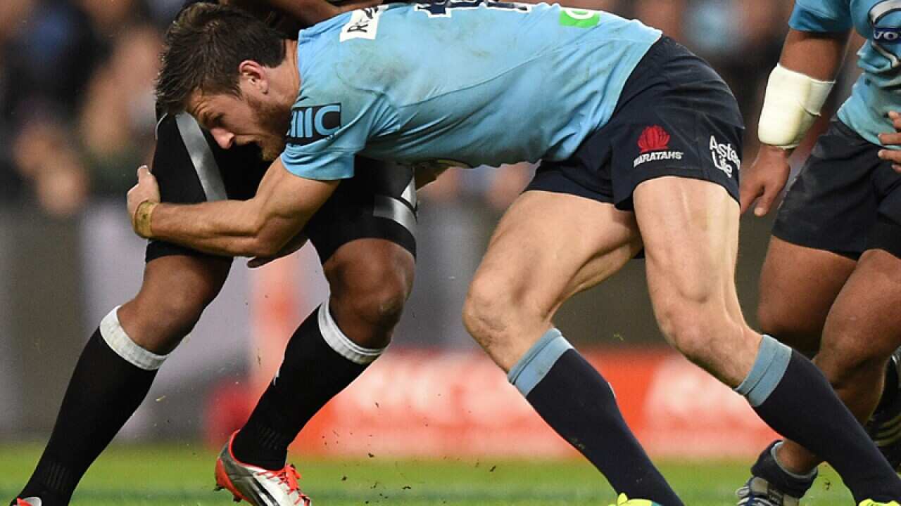 A player is tackled by Rob Horne of the Waratahs