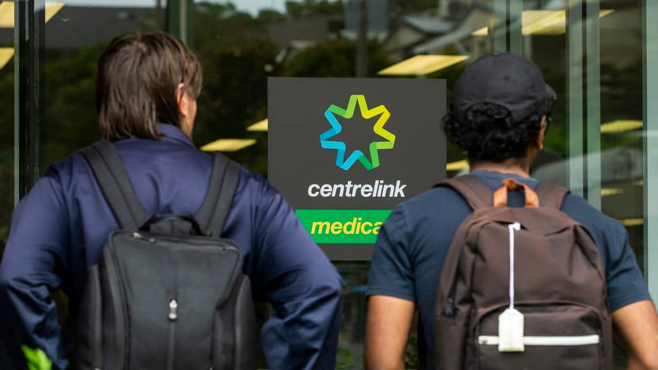 Two people standing outside a Centrelink office.