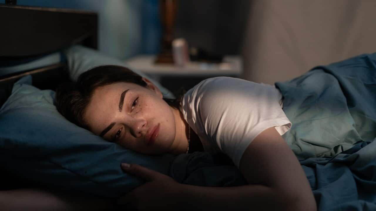 A young woman looking unhappy laying in bed