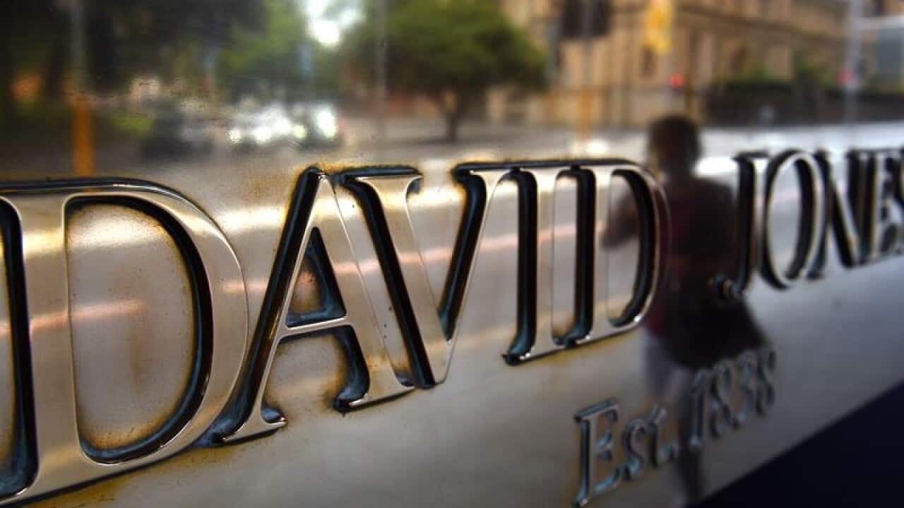 A pedestrian walk past a sign outside a David Jones department store.