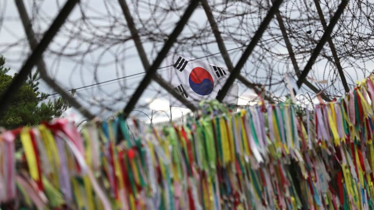 A South Korean national flag flutters near ribbons carrying messages to wish for the reunification of the two Koreas