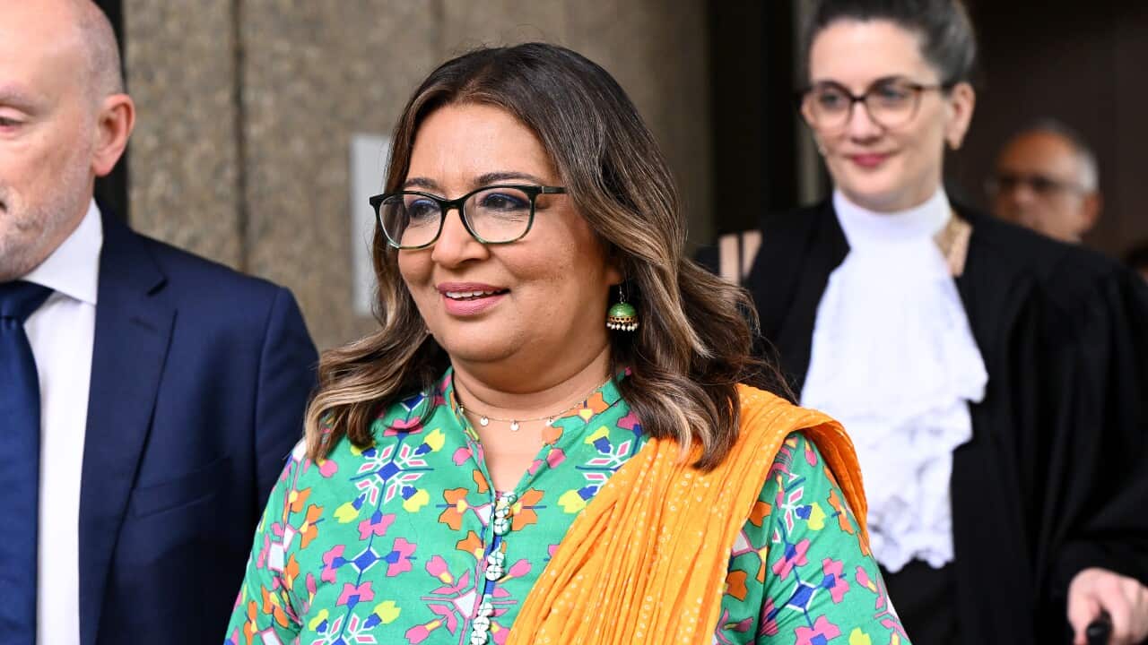 A woman in a bright outfit with glasses smiles