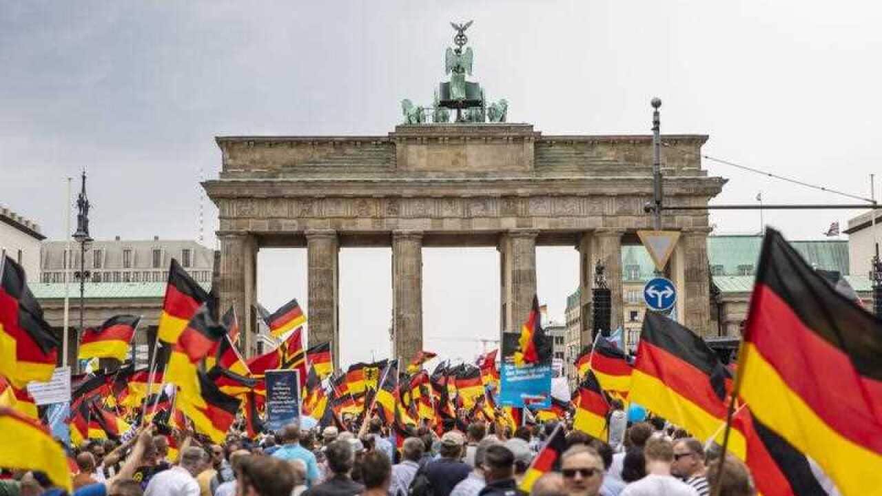 People hold German flags during a rally of the Alternative for Germany (AfD) party at the Brandenburg Gate in Berlin, Germany, 27 May 2018.