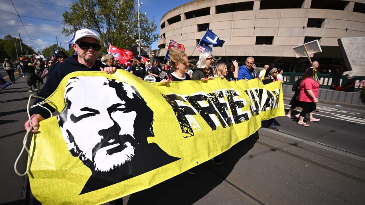 Demonstrators holding a banner that reads "FREE JULIAN" while others walk behind them.