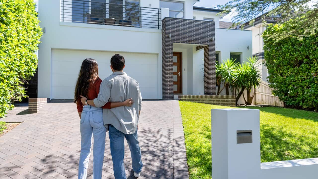 Couple standing in front of their new home