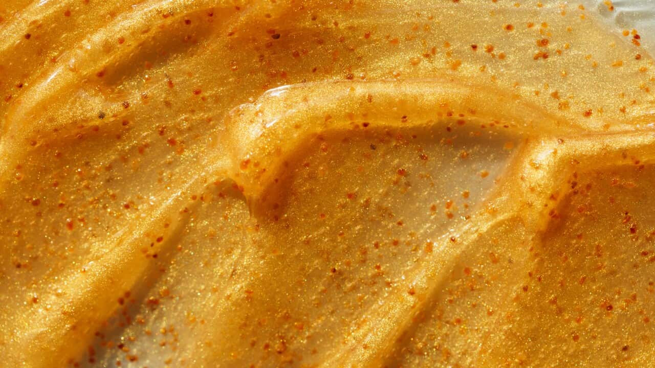 Texture of illuminating orange scrub with exfoliating particles.