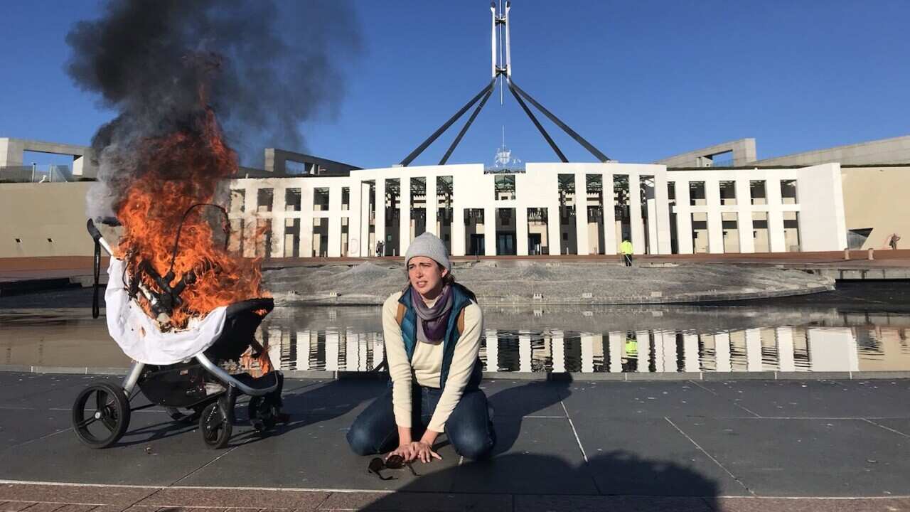 A woman with a burning pram during an Extinction Rebellion protest outside Parliament House