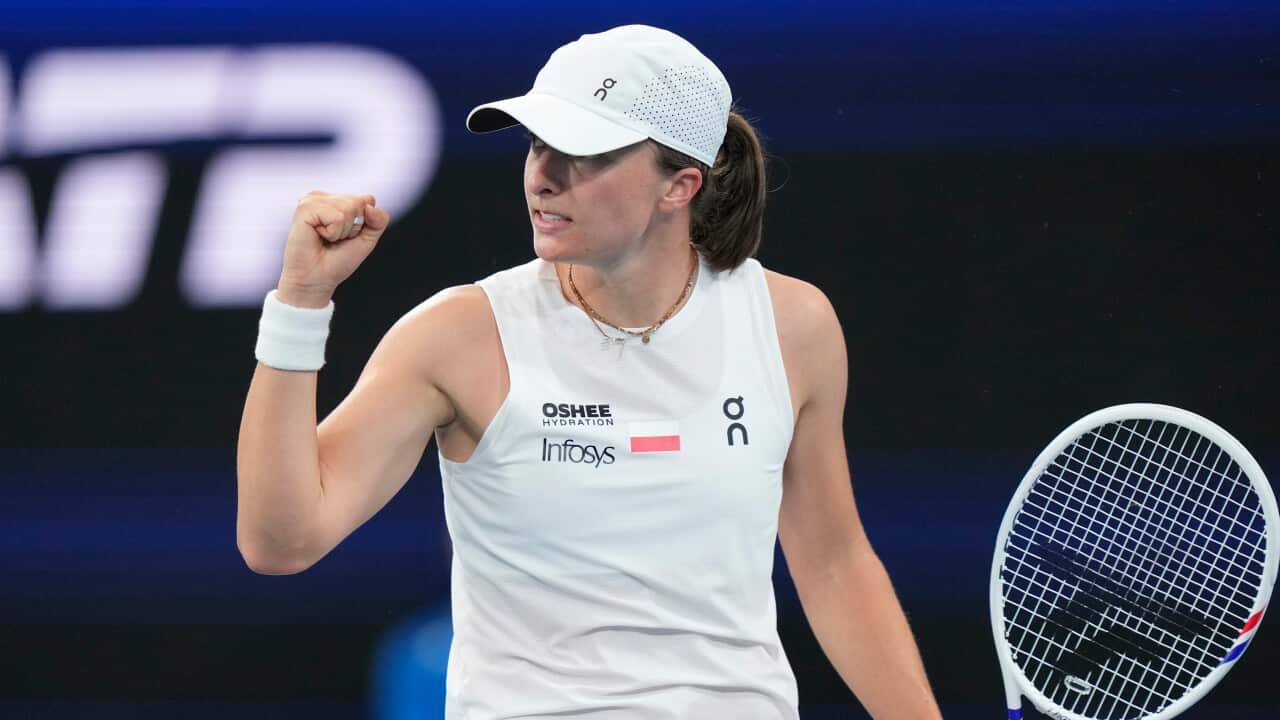 A woman holding a tennis racquet and raising a fist in the air.