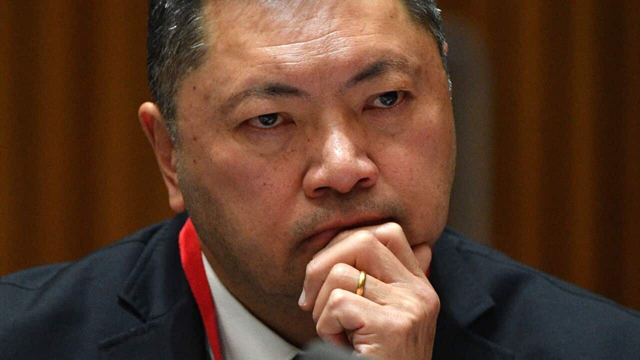 A man sitting down with his hand on his chin.