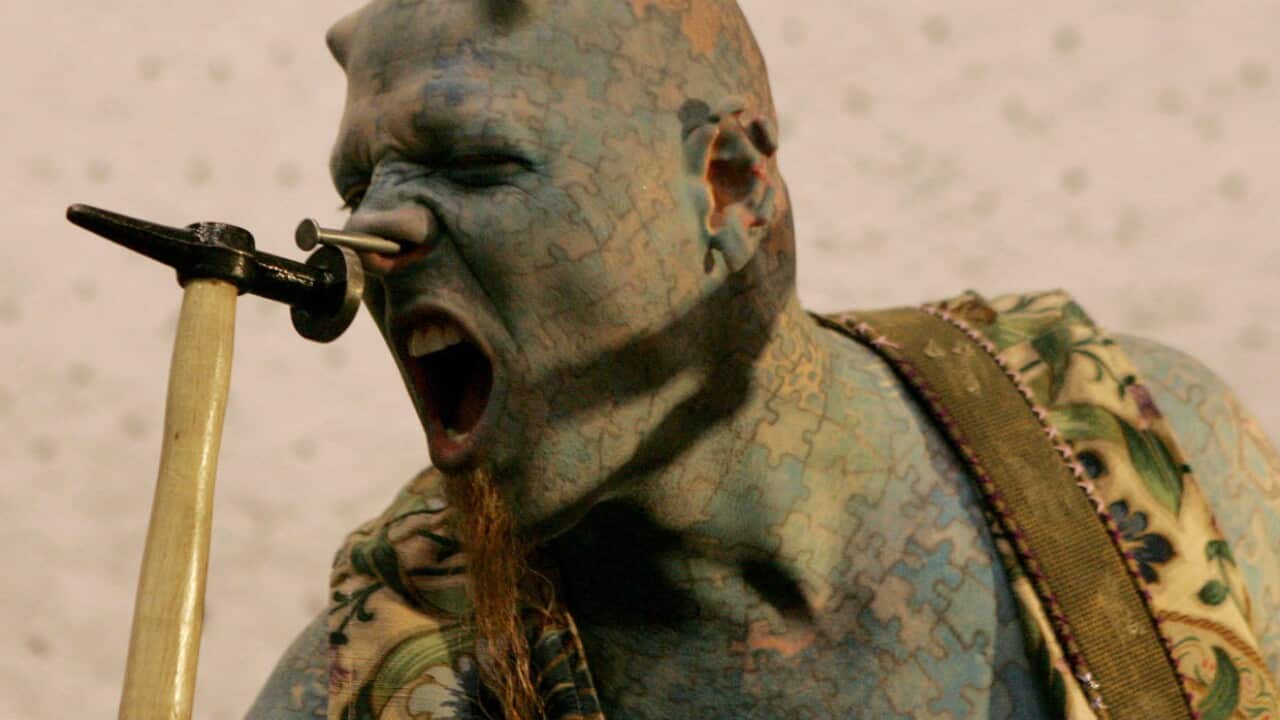 US artist known as "The Enigma" hammers a nail into his nose during an international tattoo convention.