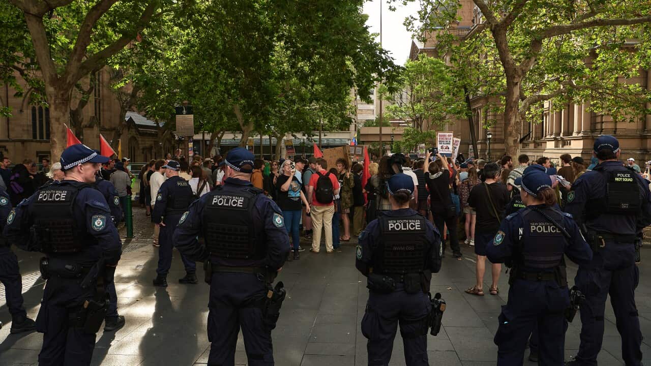 A group of police officers standing facing a group of protesters