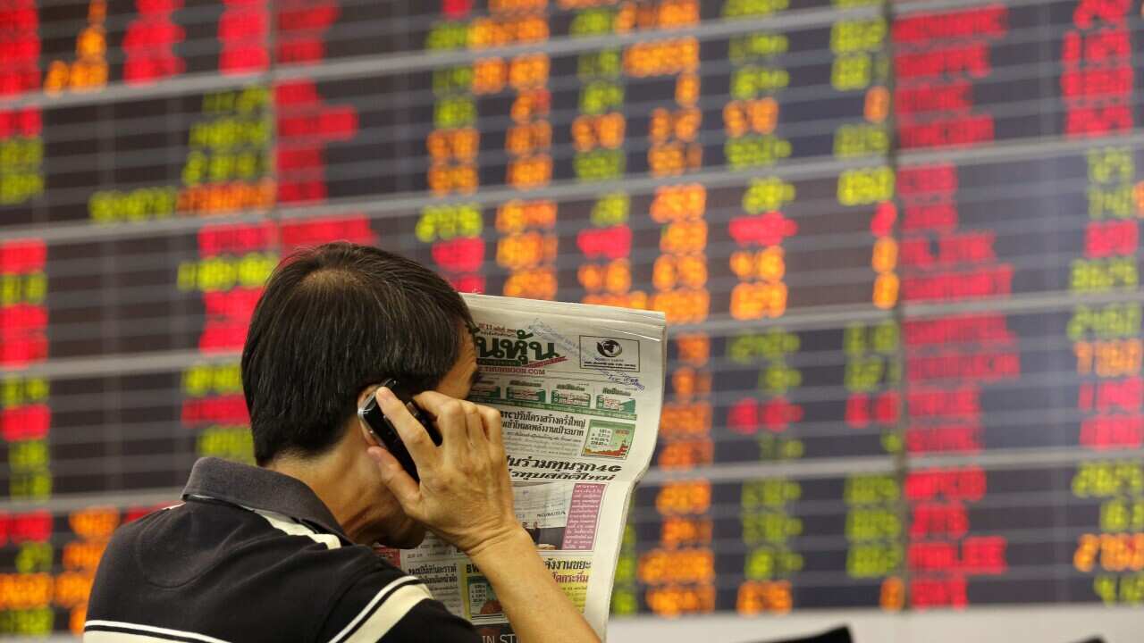 An investor reacts as he monitors share prices data displayed on electronic boards. (AAP)