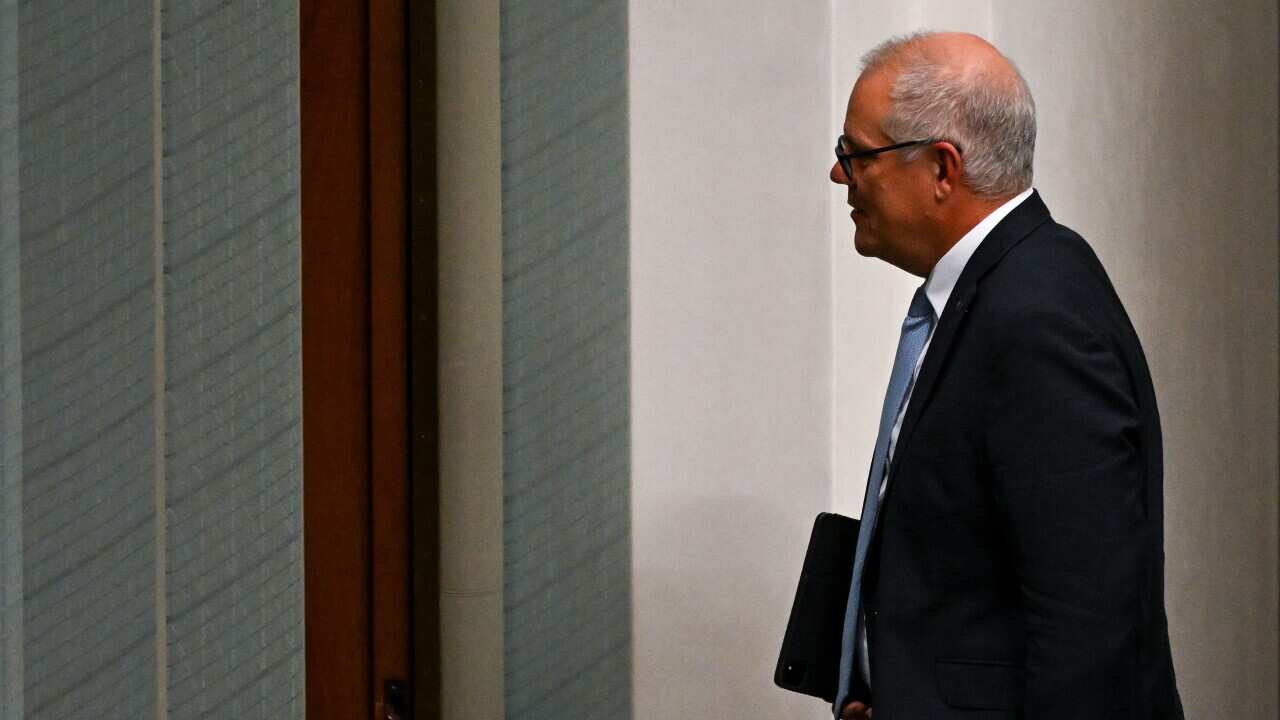 Scott Morrison walking out of a parliament chamber holding a file.