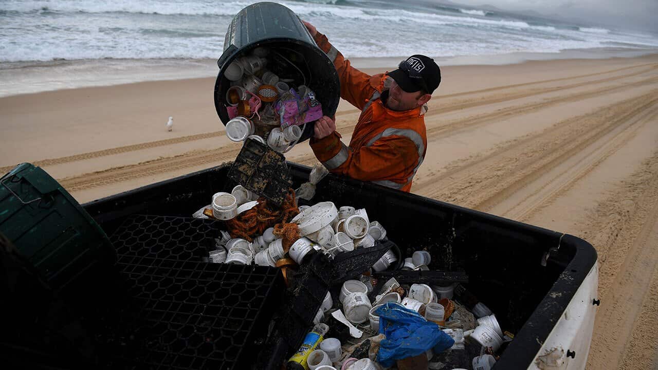 Clean up contractor Derrick Kennedy is seen clearing debris from the beach at Hawks Nest near Port Stephens.