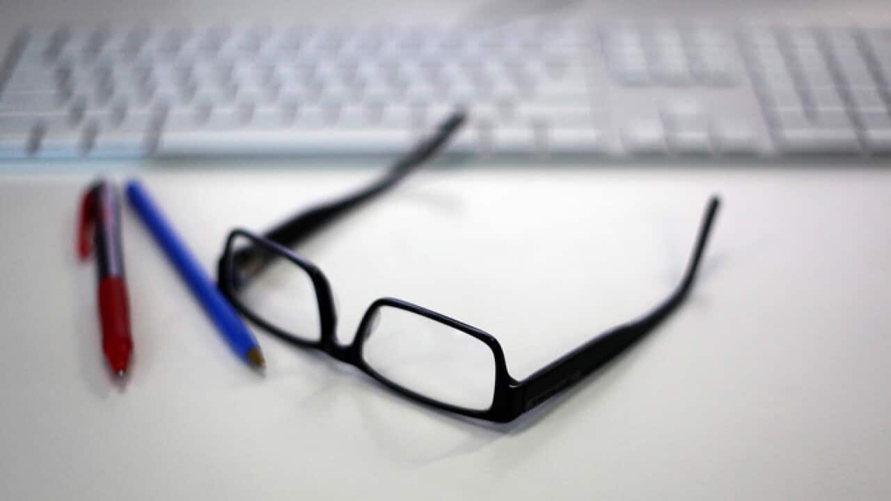 Reading glasses is featured alongside a Macintosh keyboard and office supplies in a stock image in Sydney, Wednesday, Jan. 13, 2016. (AAP Image/Sam Mooy) NO ARCHIVING