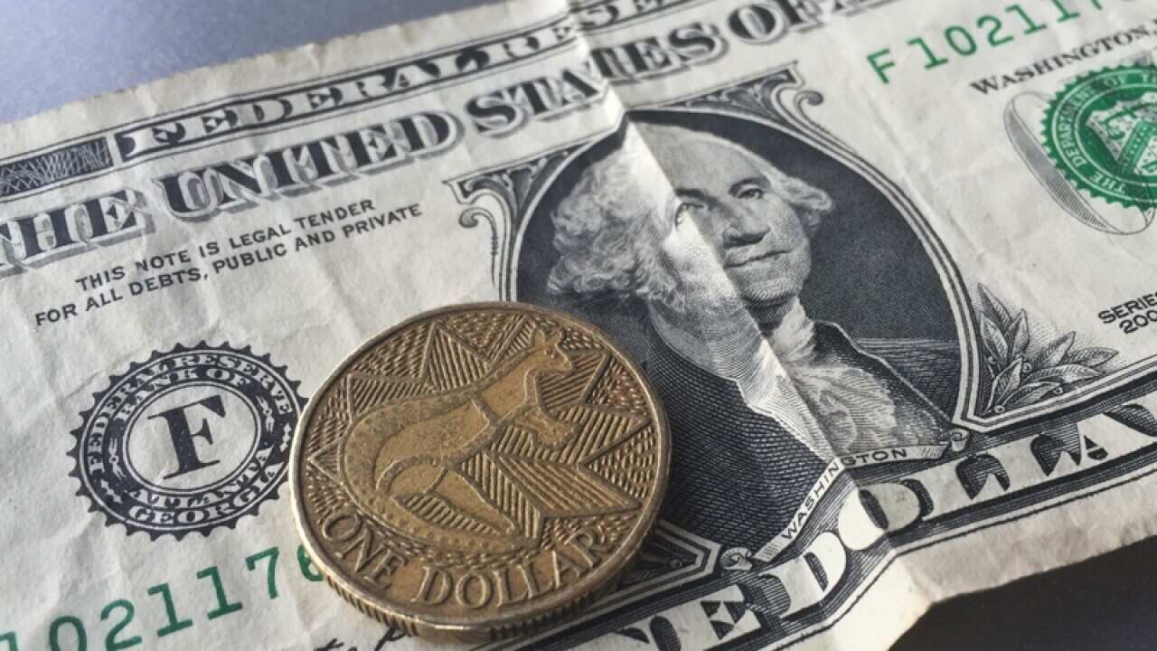 An Australian dollar coin against a backdrop of the US dollar bill
