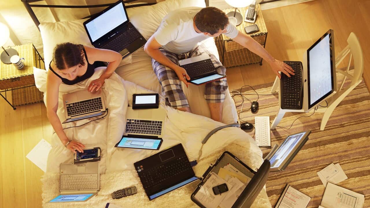 Couple in bed surrounded by computers