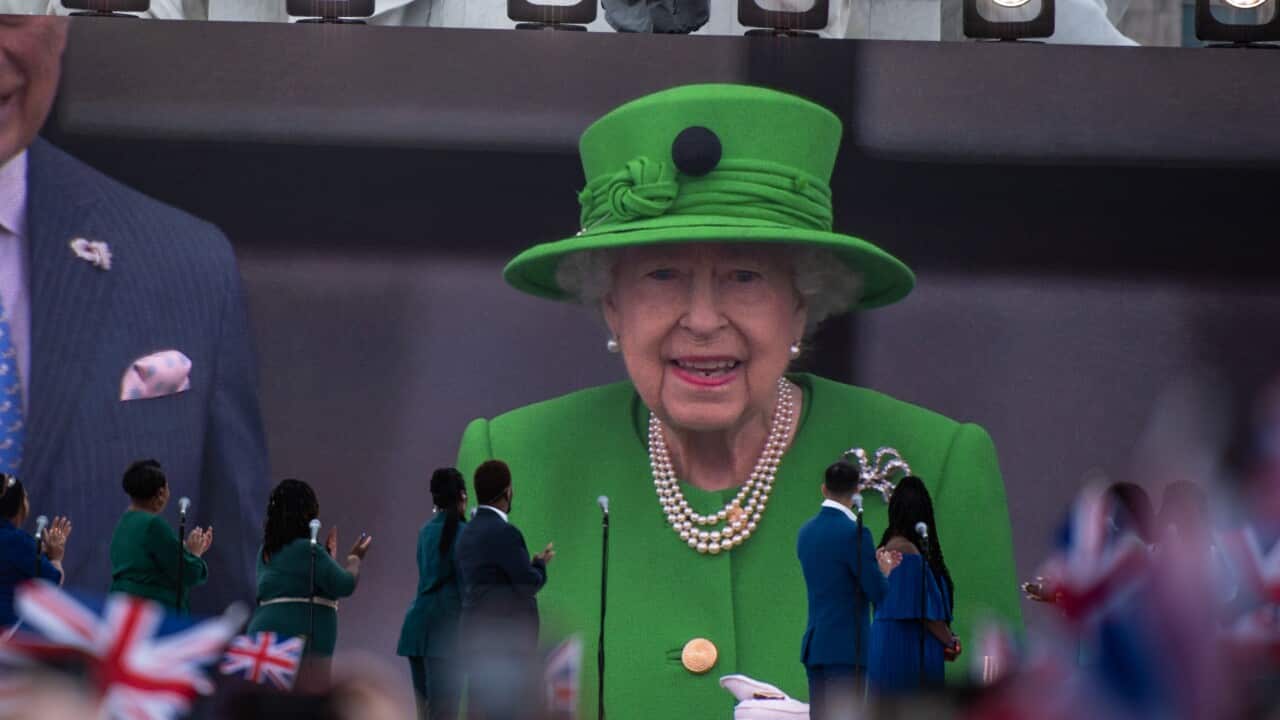 The Queen is seen on a screen that a crowd is watching.