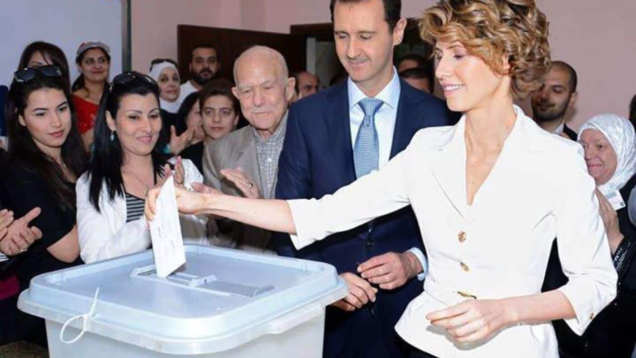 A handout picture released by the official Facebook page of Syria's First Lady Asma al-Assad shows Syrian President Bashar al-Assad (C) watching on as his wife Asma casts her vote. (AAP)