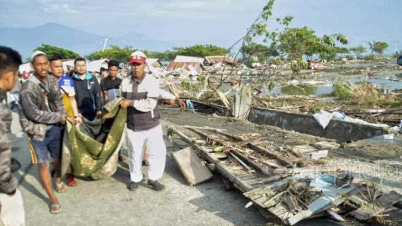People carry the body of a tsunami victim in Palu, Indonesia