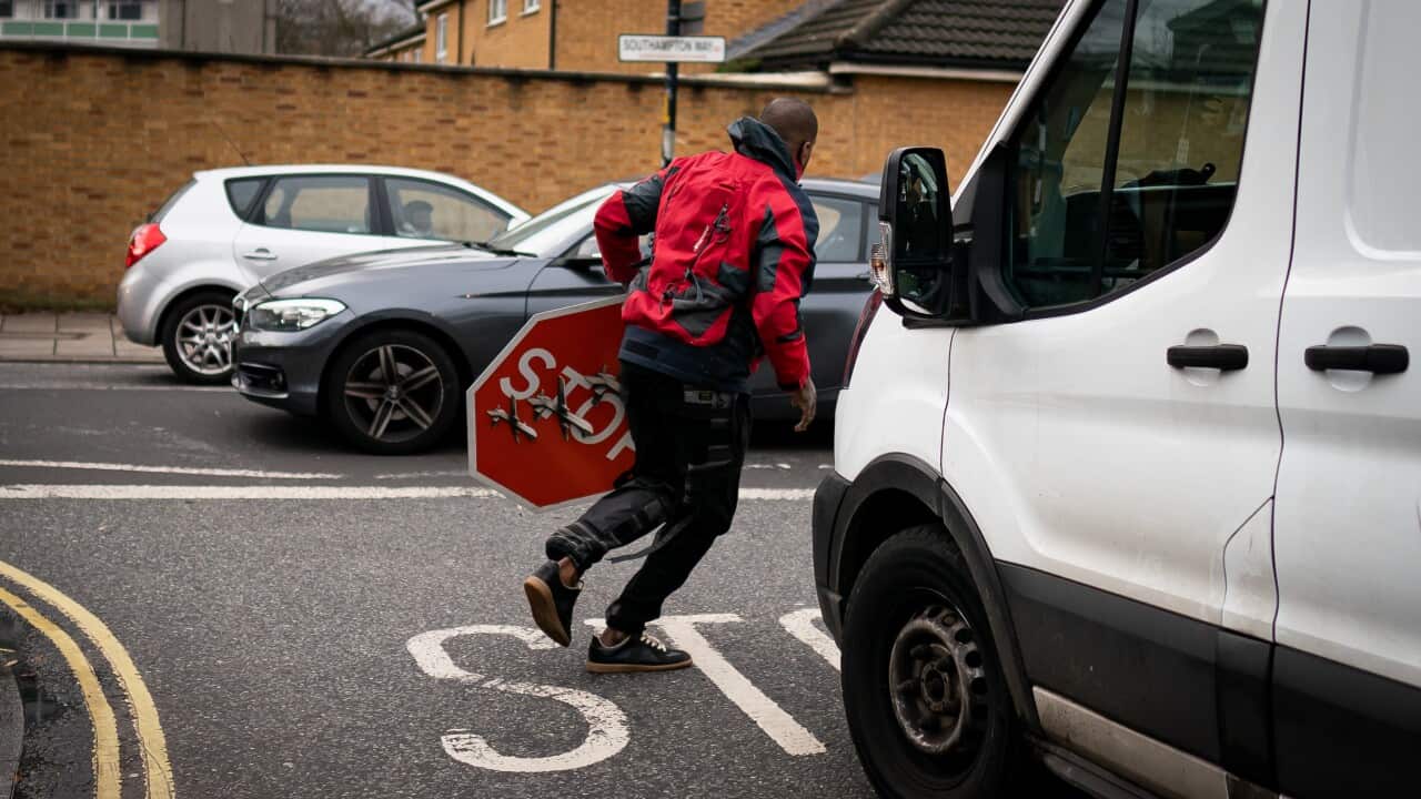A man running away holding a stop sign