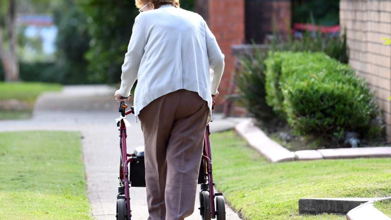 An elderly woman uses a mobility walker