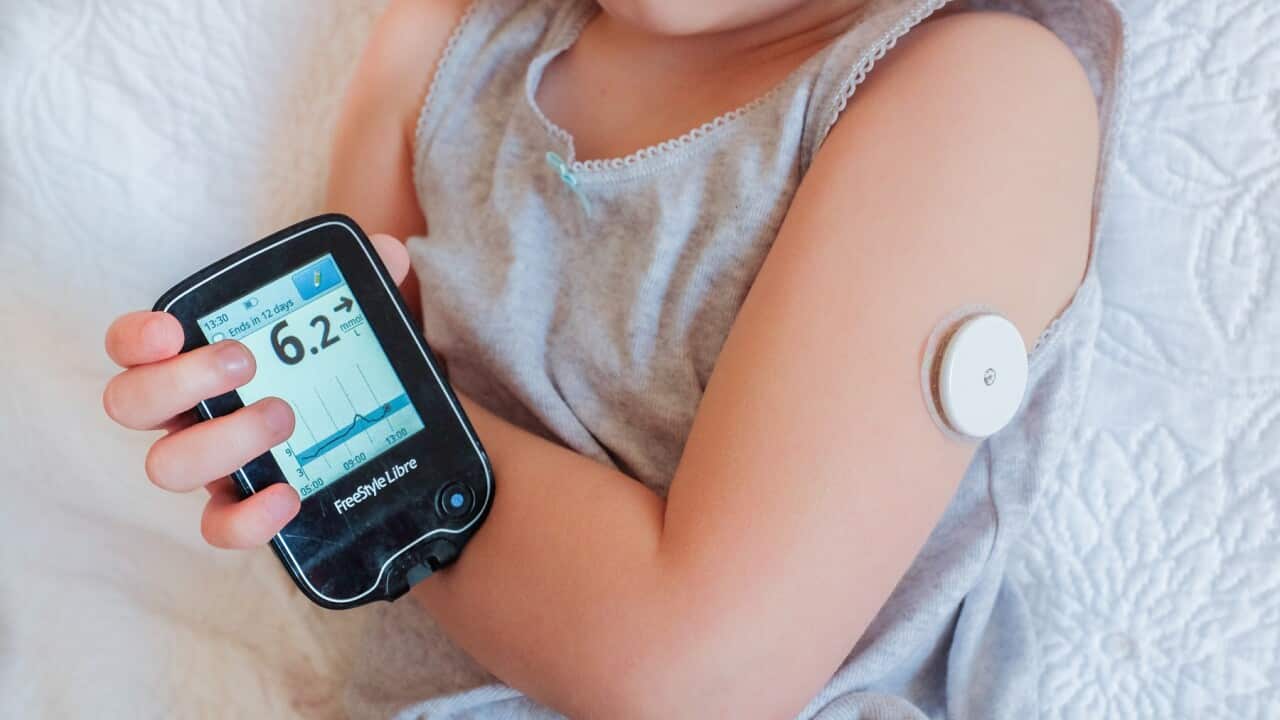 A child checks her blood sugar by scanning a Glucose sensor (AAP).