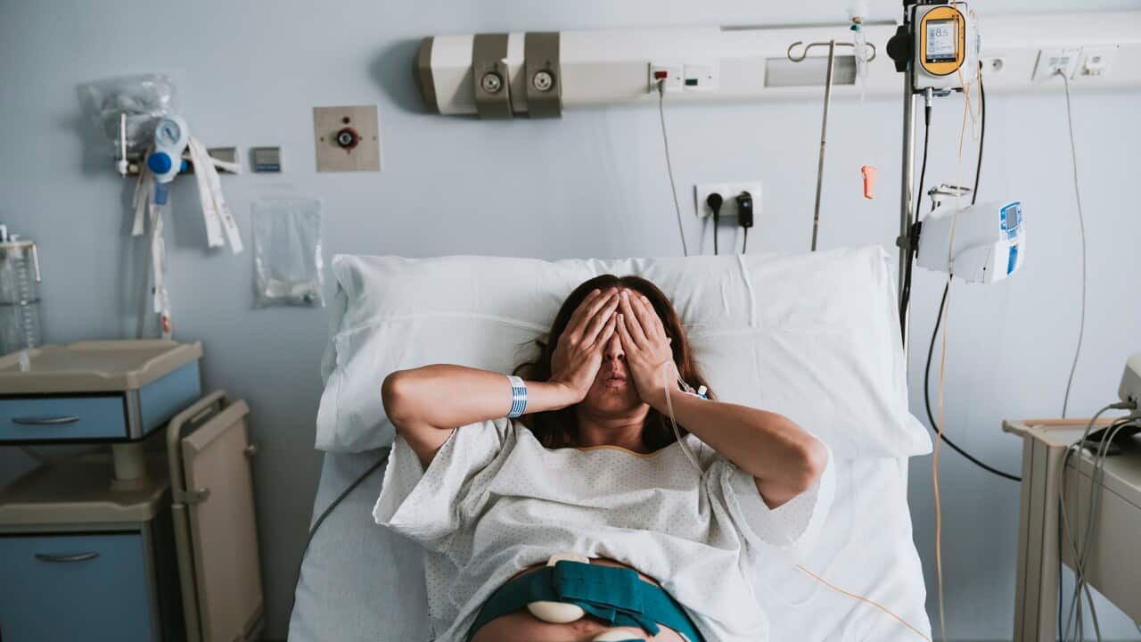 Stressed pregnant woman lying on bed in hospital