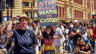 A protester holds a placard reading "Stop black deaths in custody' at a rally in Sydney