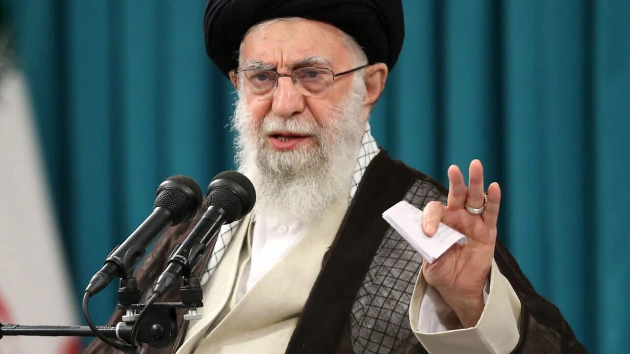 A man who is speaking while seated in front of a microphone.