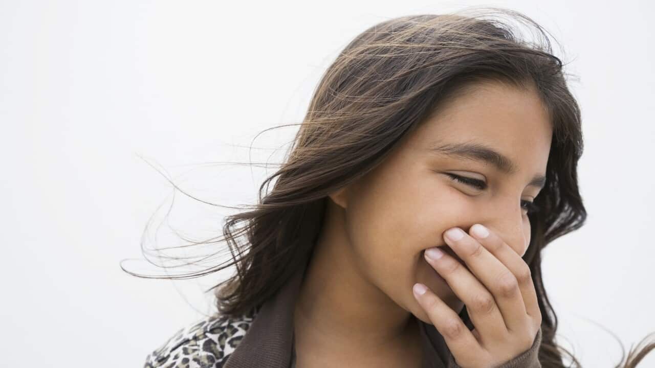 Brunette girl laughing covering mouth with hand