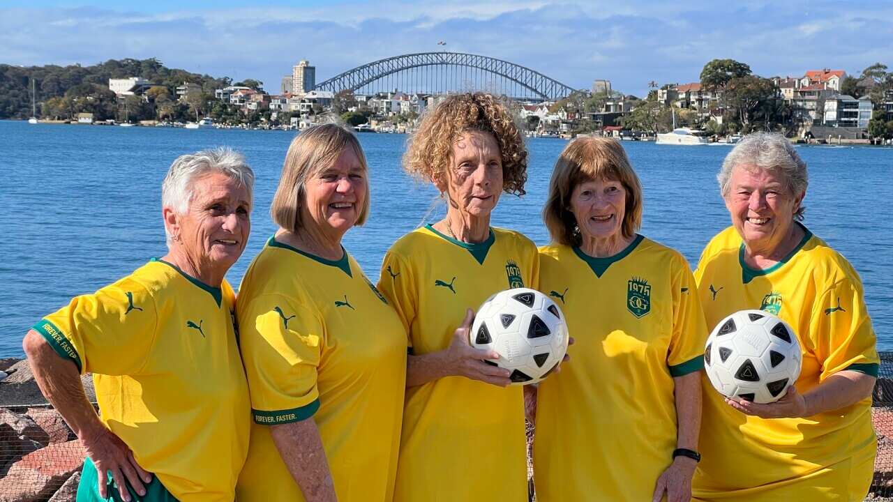 Five women wearing Australian football outfits
