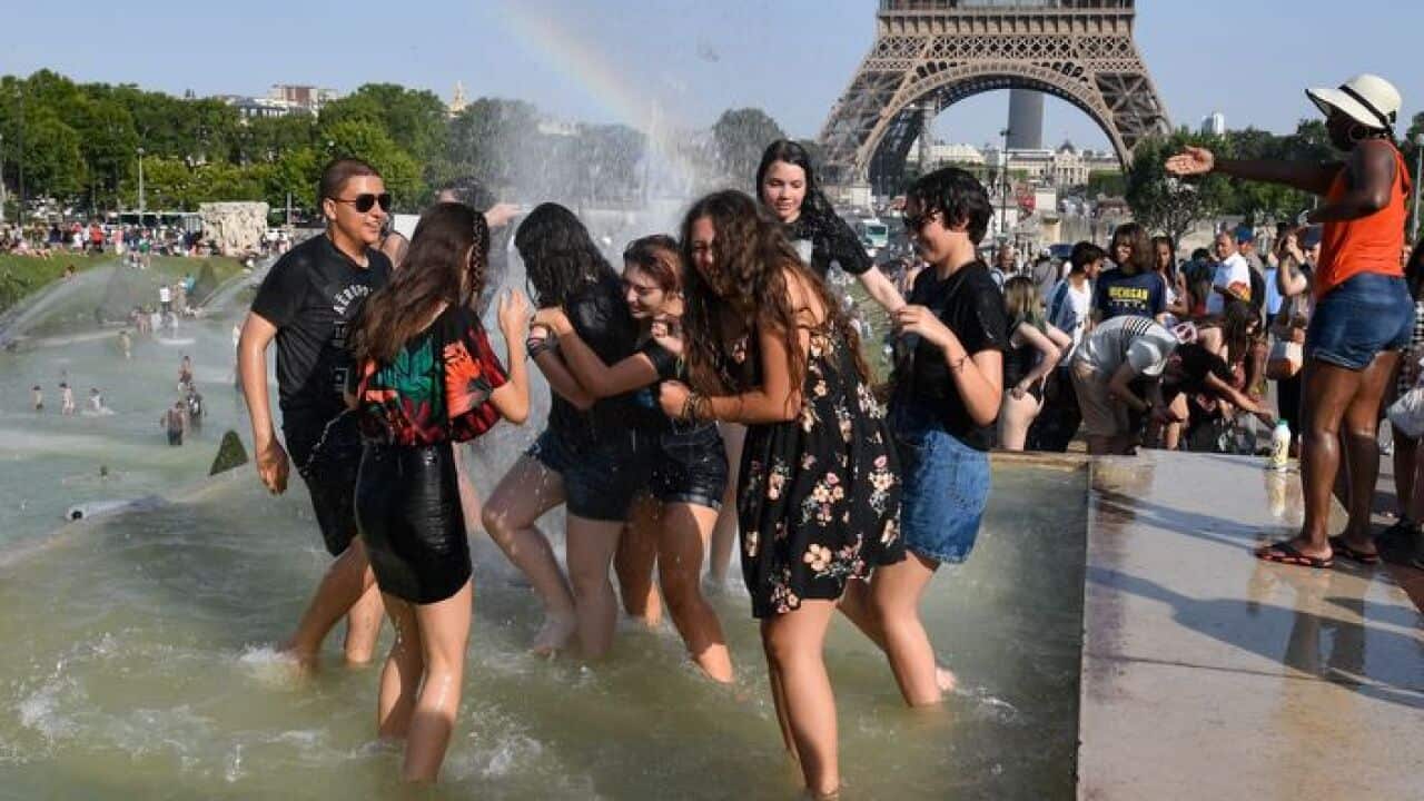 People cool off at the Trocadero Fountains next to the Eiffel Tower in Paris