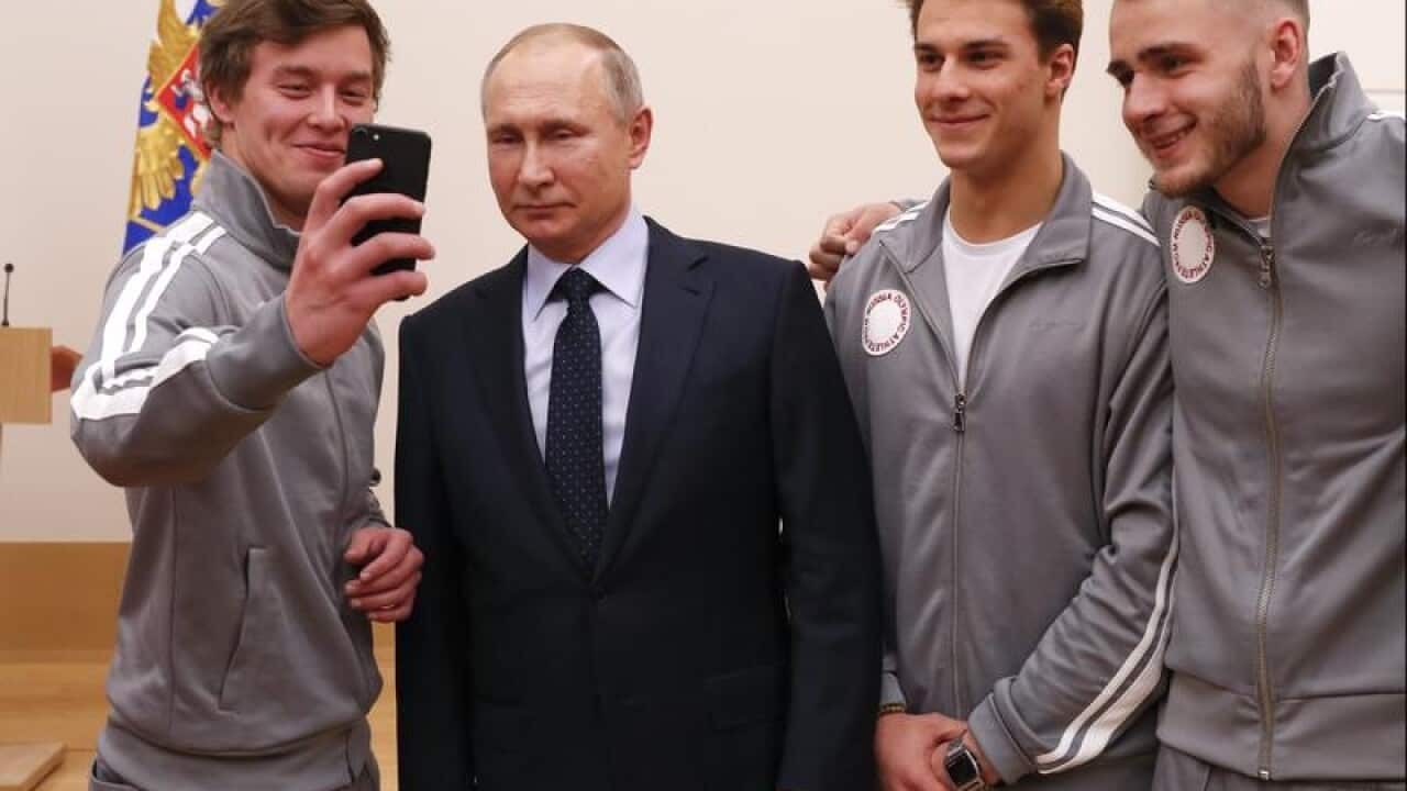 Vladimir Putin poses with Russian athletes.
