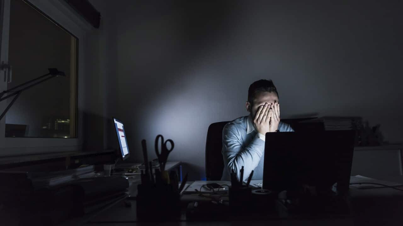 Exhausted businessman sitting at desk in office at night