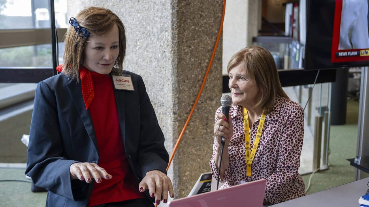 A woman speaks to a humanoid robot.