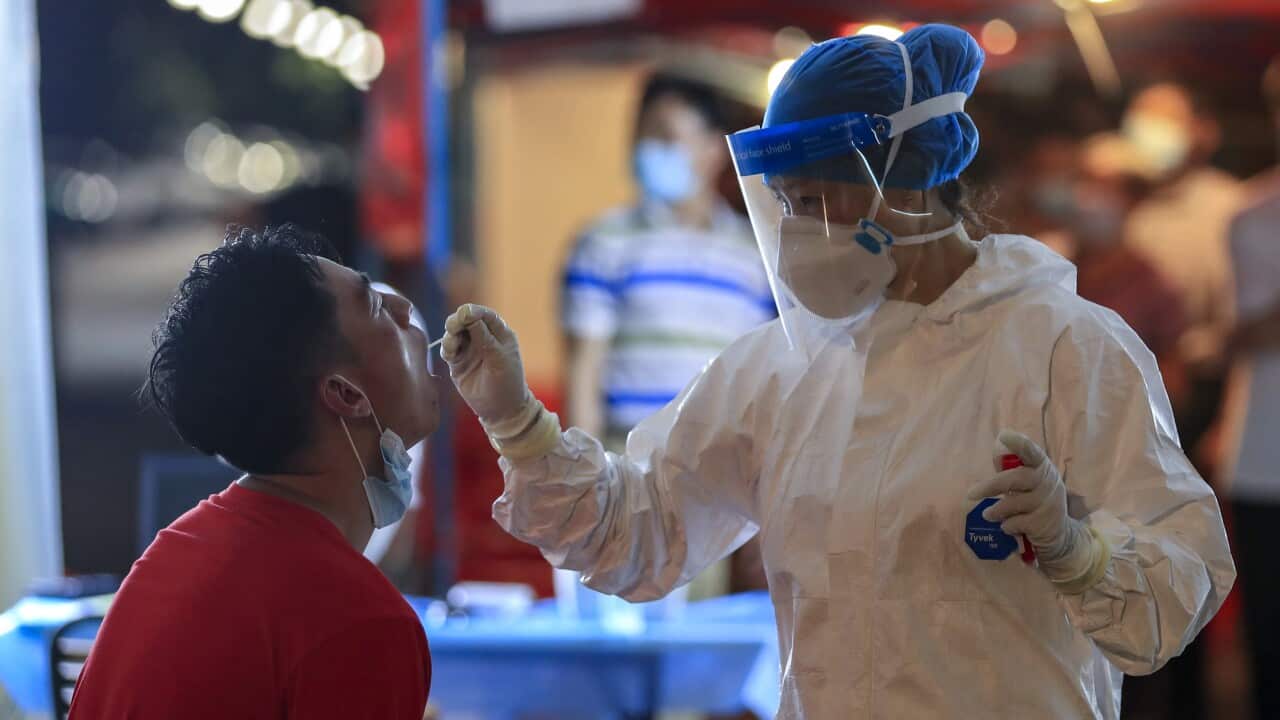 A medical worker wearing PPE takes swab sample from a resident during a COVID-19 test