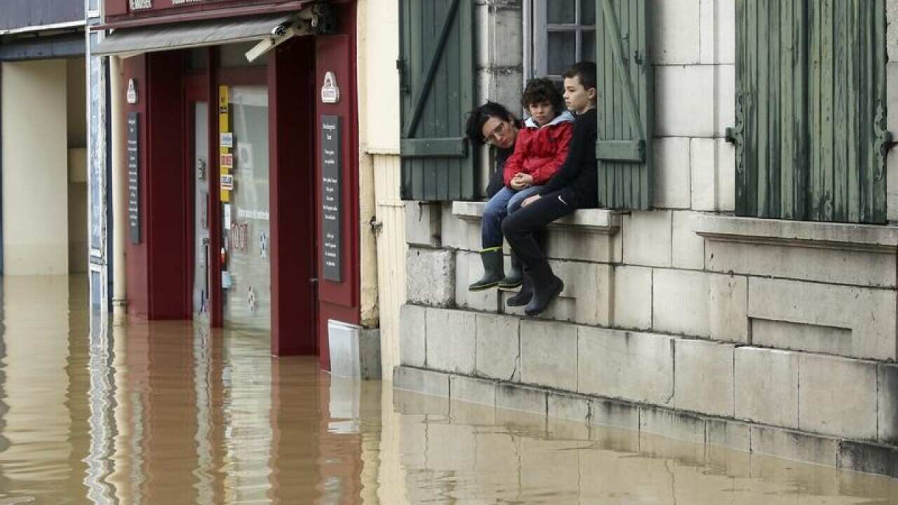 A mother and her children watch the level of flooded water in France.