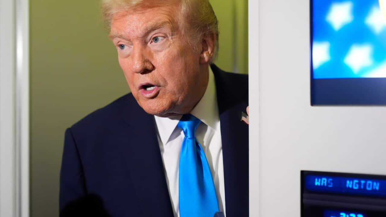 US President Donald Trump stands in doorway in suit and blue tie