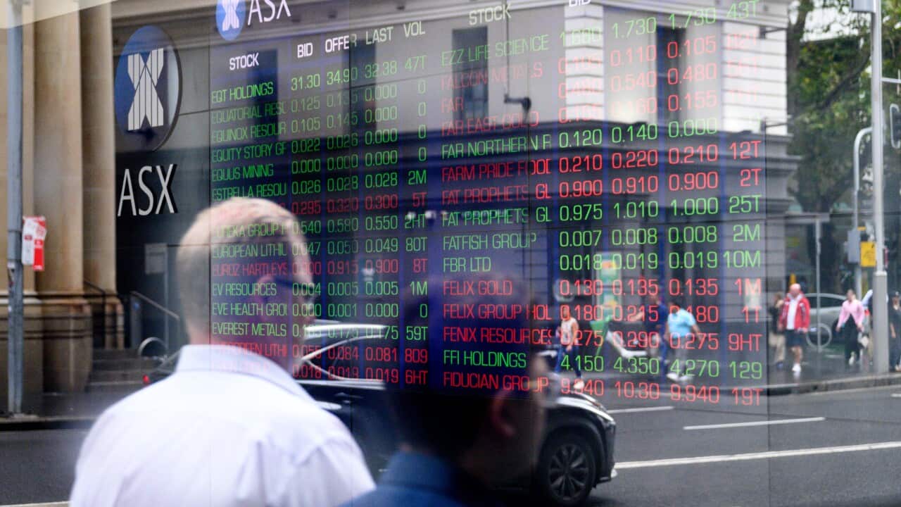 A reflection of people walking past a building with a sign on it reading ASX