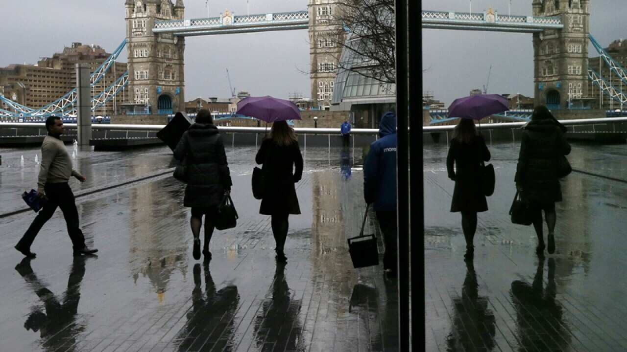 Pedestrians are reflected in the window as they walk through rain