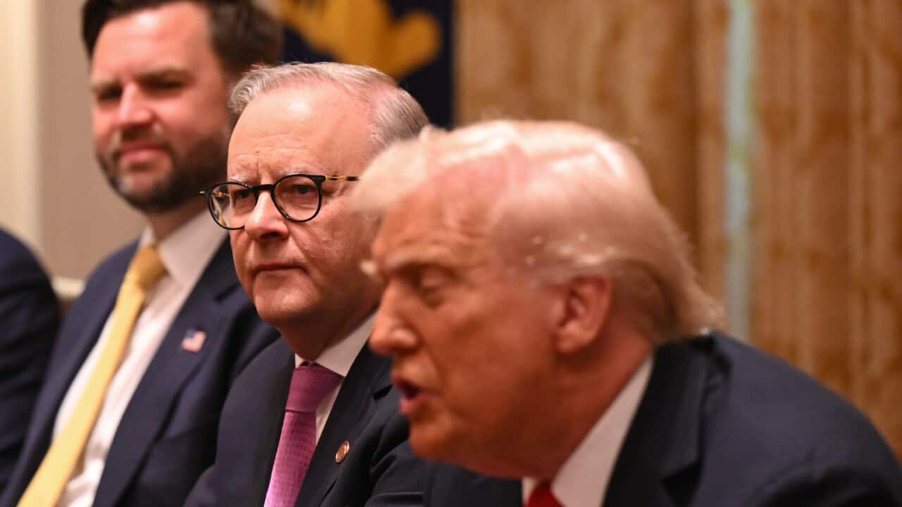 Three men sitting next to each other wearing suits
