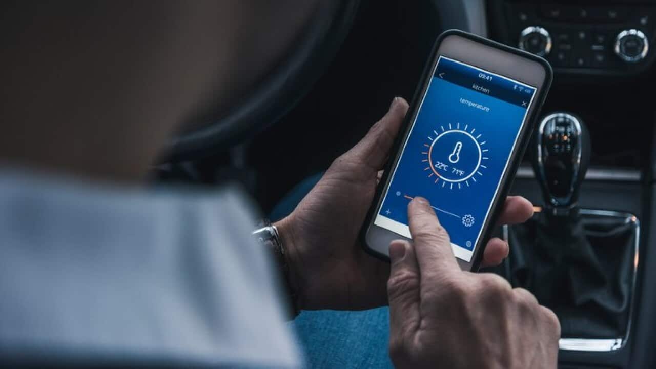 A man in a car adjusting smart home devices remotely